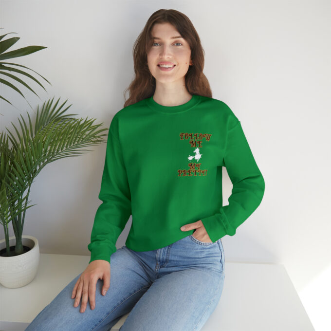 A woman sitting on the ground wearing jeans and green sweatshirt.