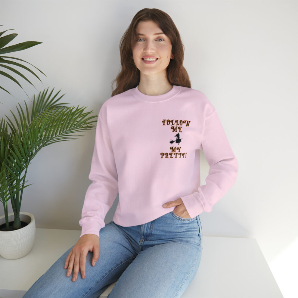 A woman sitting on the ground wearing jeans and a pink sweatshirt.