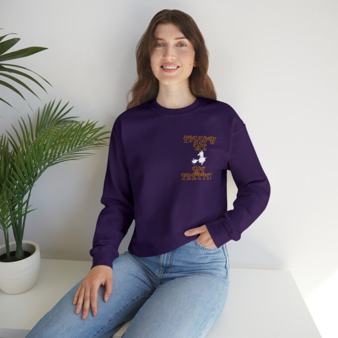 A woman sitting on the ground wearing jeans and a purple sweatshirt.