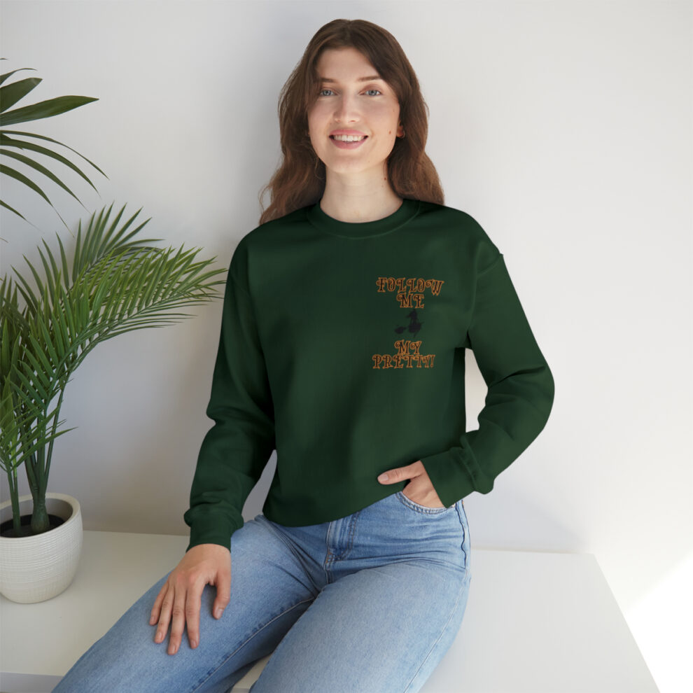 A woman sitting on the ground wearing jeans and a green sweatshirt.