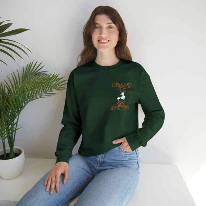 A woman sitting on the ground wearing jeans and a green sweatshirt.