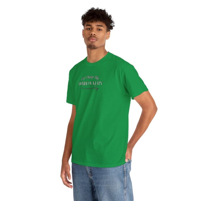 A man in green shirt and jeans standing next to a wall.