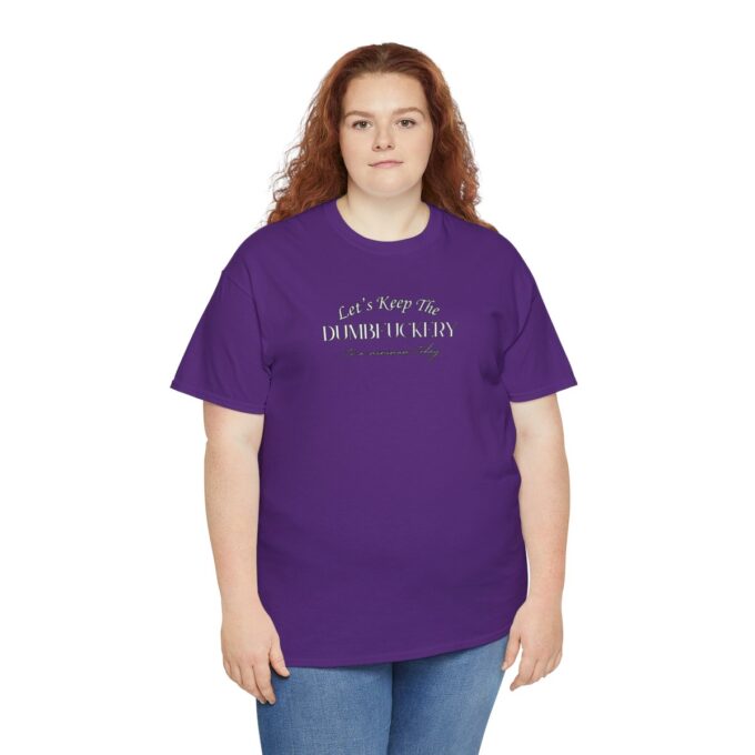 A woman wearing purple shirt and jeans standing next to wall.